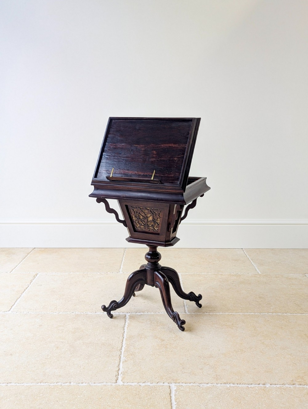 A dark brown rosewood Victorian sewing and reading table featuring an adjustable slanted lid with brass page holders, carved fretwork sides, a turned pedestal column, and four scrolled feet. View IX