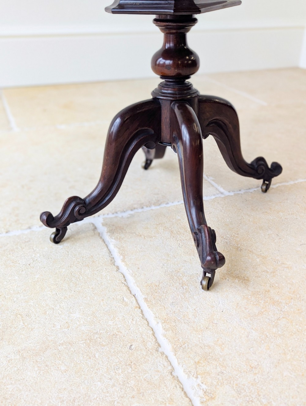 A dark brown rosewood Victorian sewing and reading table featuring an adjustable slanted lid with brass page holders, carved fretwork sides, a turned pedestal column, and four scrolled feet. View XVII