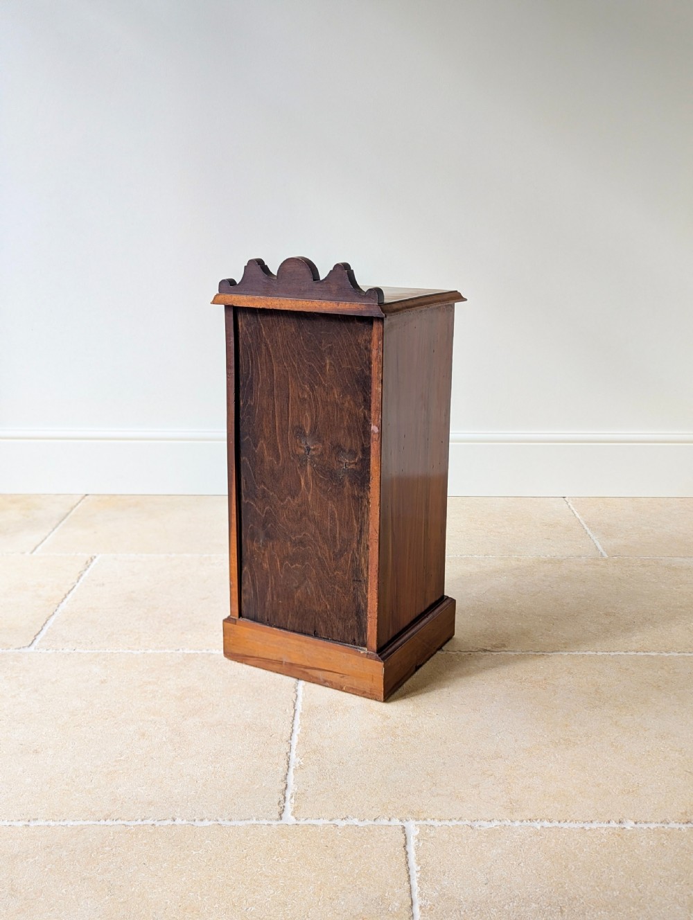A late Victorian mahogany and exotic wood bedside cupboard featuring a carved top gallery, panelled door with brass drop handle, and a solid plinth base. View XVIII