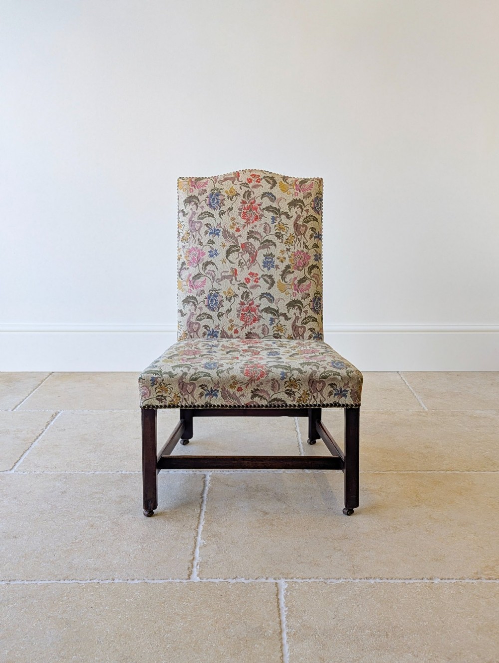 A mid-19th century Victorian side chair with dark mahogany legs on brass castors and dense floral upholstery framed with brass studding. View III