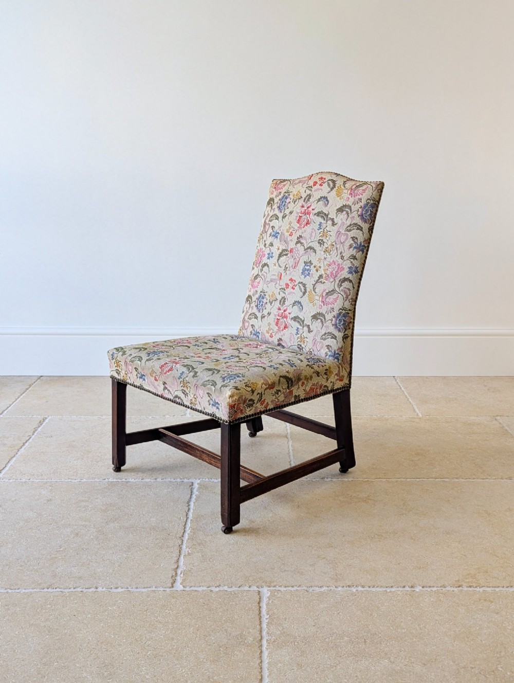 A mid-19th century Victorian side chair with dark mahogany legs on brass castors and dense floral upholstery framed with brass studding. View V