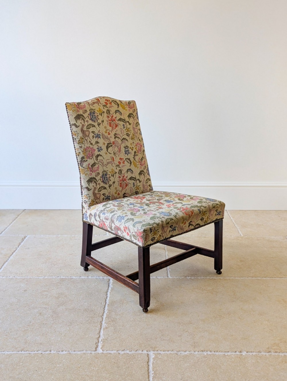 A mid-19th century Victorian side chair with dark mahogany legs on brass castors and dense floral upholstery framed with brass studding. View VI