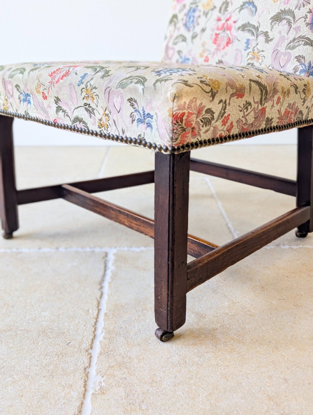 A mid-19th century Victorian side chair with dark mahogany legs on brass castors and dense floral upholstery framed with brass studding. View XV
