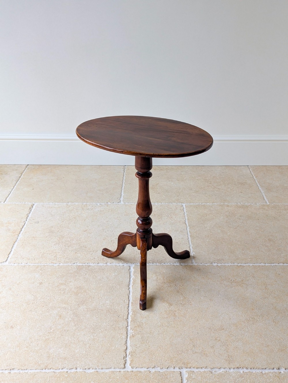An antique Georgian mahogany wine table featuring a smooth oval top, turned central column, and three cabriole tripod legs. View II