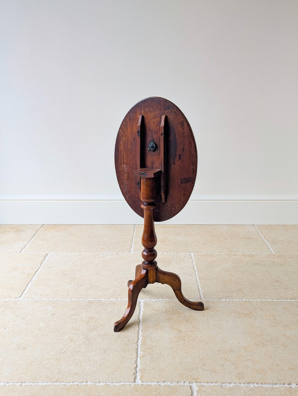 An antique Georgian mahogany wine table featuring a smooth oval top, turned central column, and three cabriole tripod legs. View IV