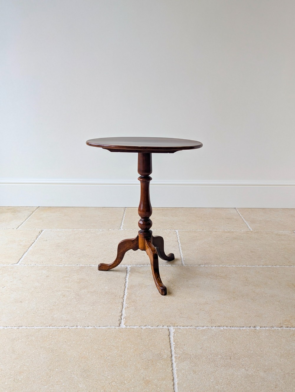 An antique Georgian mahogany wine table featuring a smooth oval top, turned central column, and three cabriole tripod legs. View V