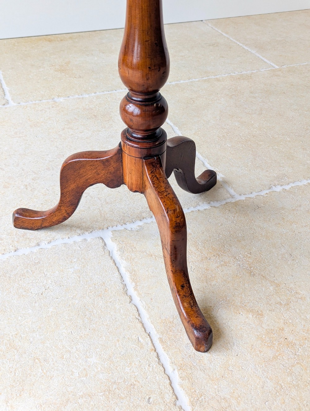 An antique Georgian mahogany wine table featuring a smooth oval top, turned central column, and three cabriole tripod legs. View VI