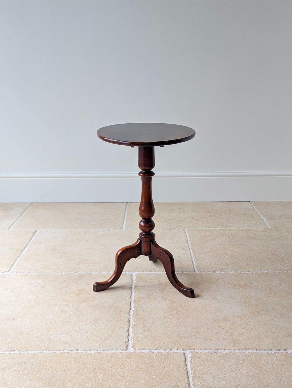 An antique Georgian mahogany wine table featuring a smooth oval top, turned central column, and three cabriole tripod legs. View VII