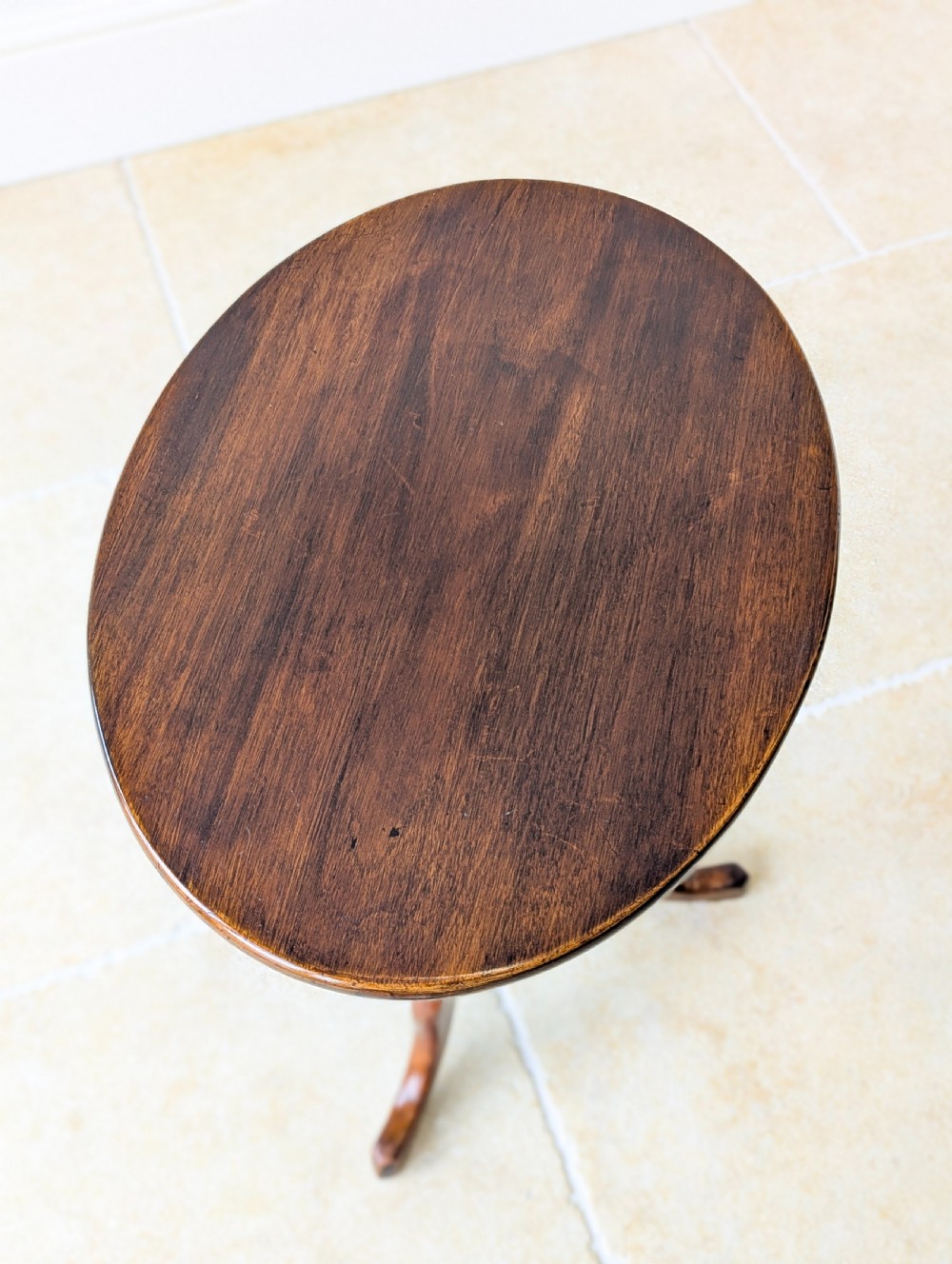 An antique Georgian mahogany wine table featuring a smooth oval top, turned central column, and three cabriole tripod legs. View VIII