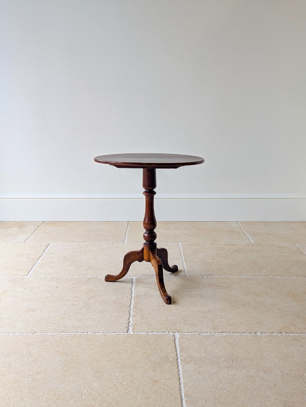 An antique Georgian mahogany wine table featuring a smooth oval top, turned central column, and three cabriole tripod legs. View IX