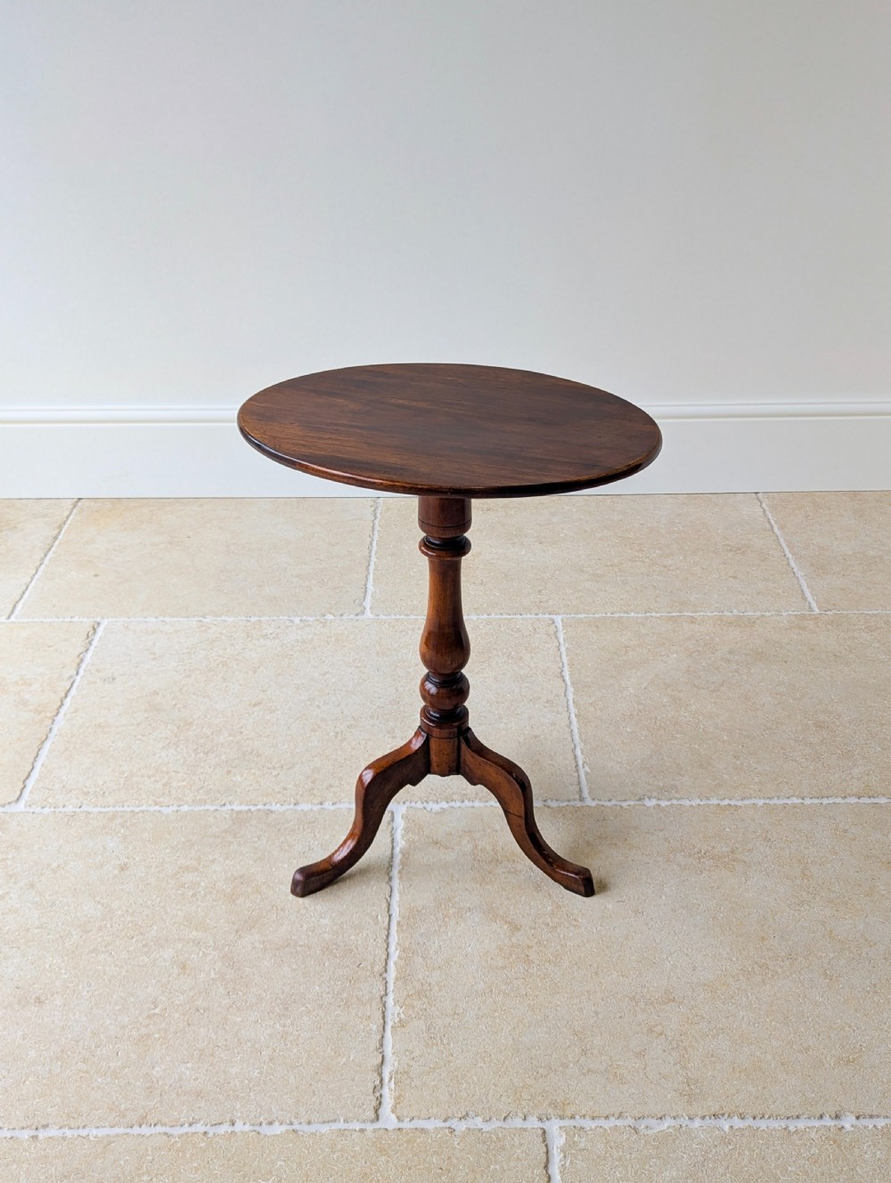 An antique Georgian mahogany wine table featuring a smooth oval top, turned central column, and three cabriole tripod legs. View X