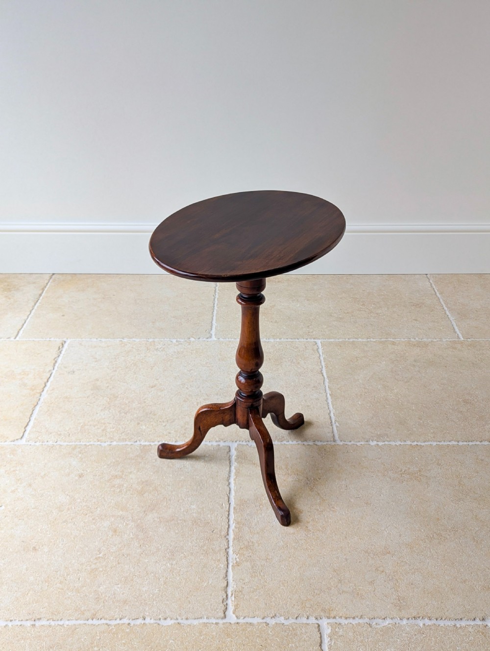 An antique Georgian mahogany wine table featuring a smooth oval top, turned central column, and three cabriole tripod legs. View XIV