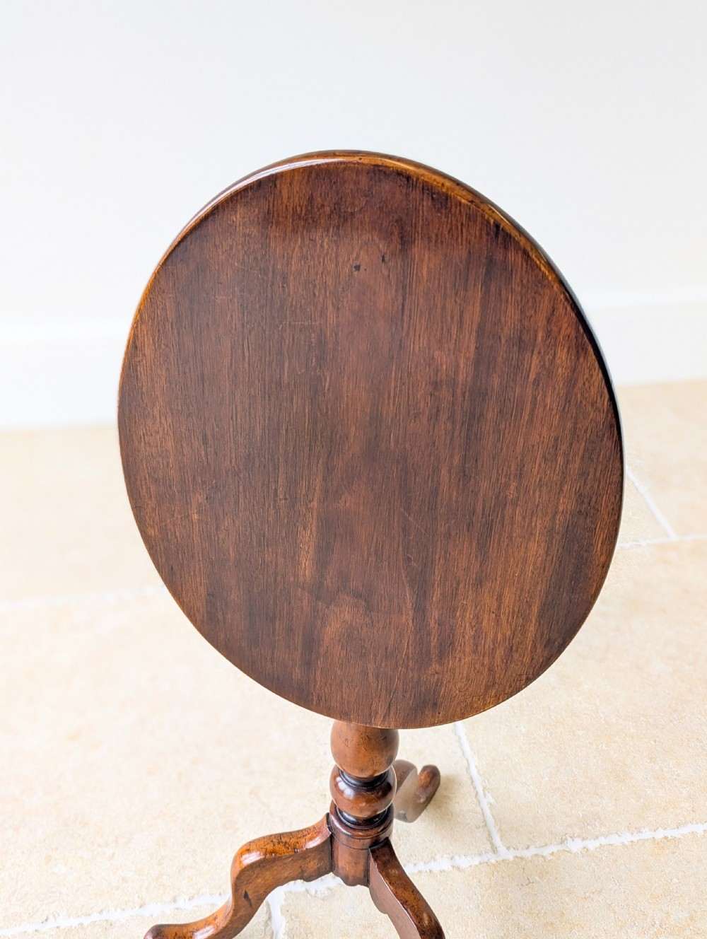 An antique Georgian mahogany wine table featuring a smooth oval top, turned central column, and three cabriole tripod legs. View XV