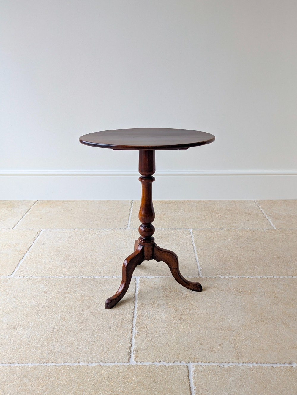 An antique Georgian mahogany wine table featuring a smooth oval top, turned central column, and three cabriole tripod legs. View XVI