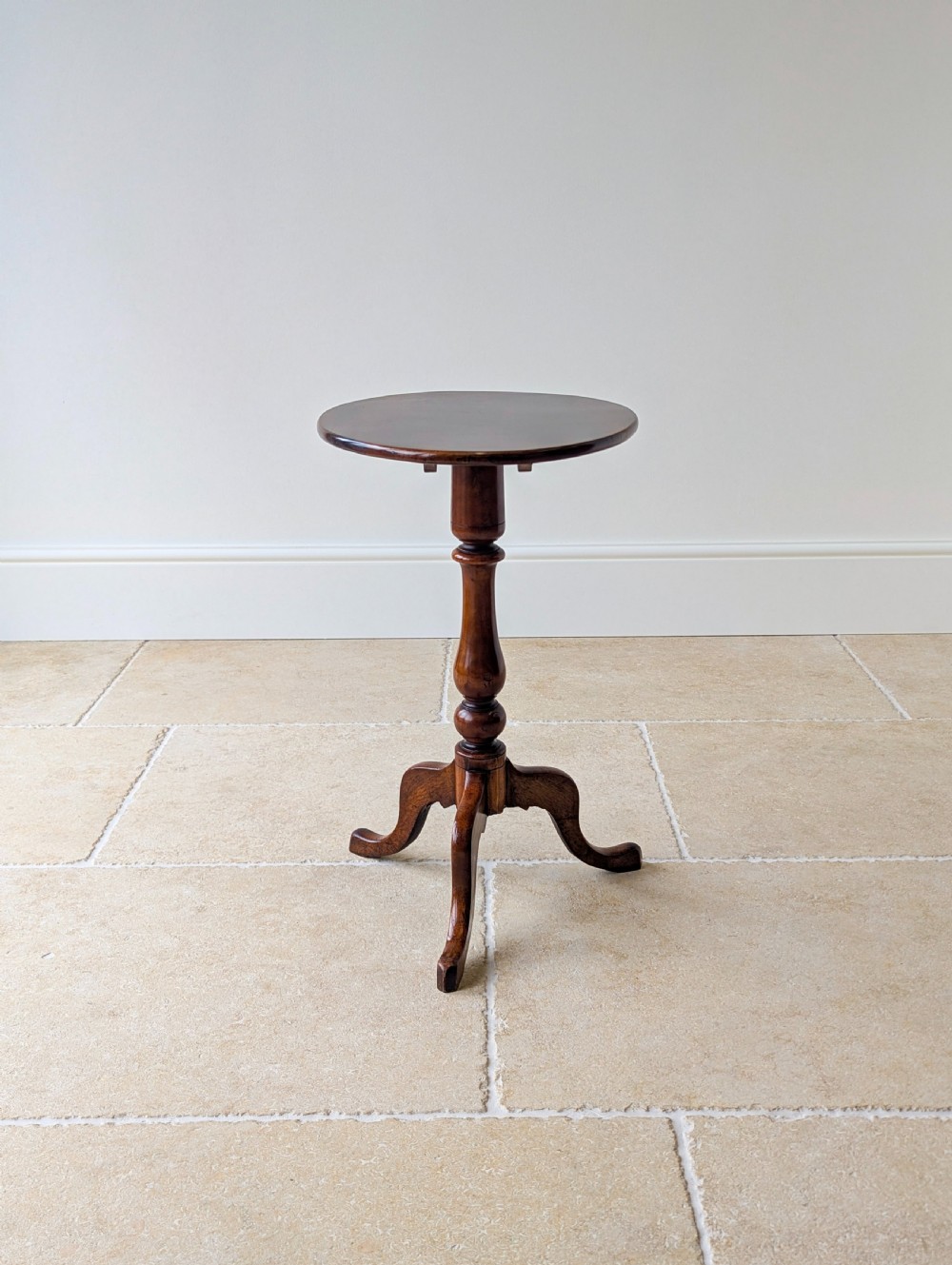An antique Georgian mahogany wine table featuring a smooth oval top, turned central column, and three cabriole tripod legs. View XVII