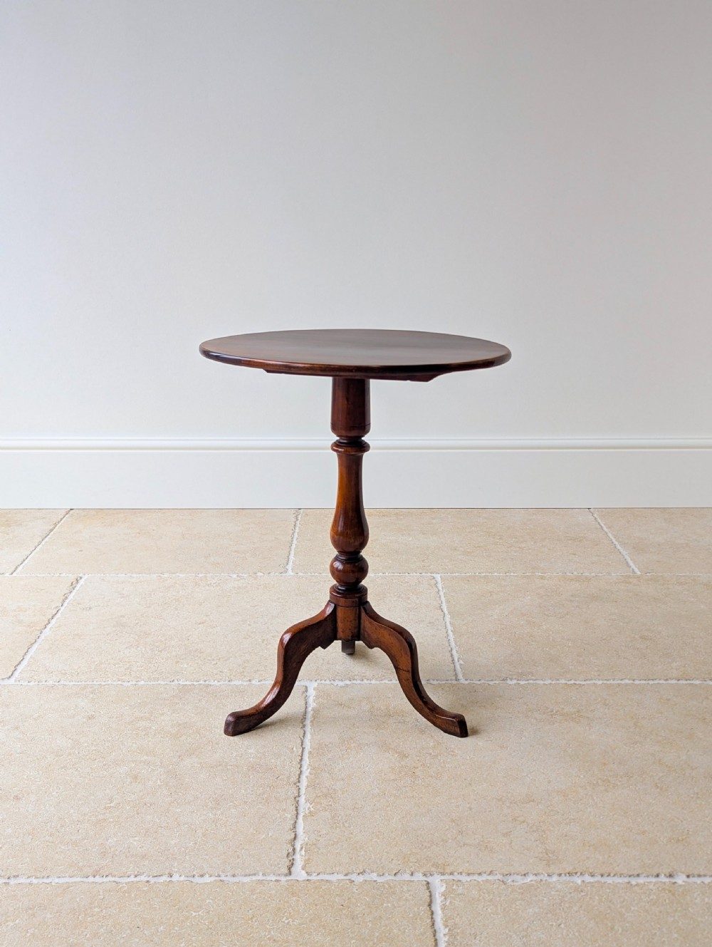 An antique Georgian mahogany wine table featuring a smooth oval top, turned central column, and three cabriole tripod legs. View XVIII