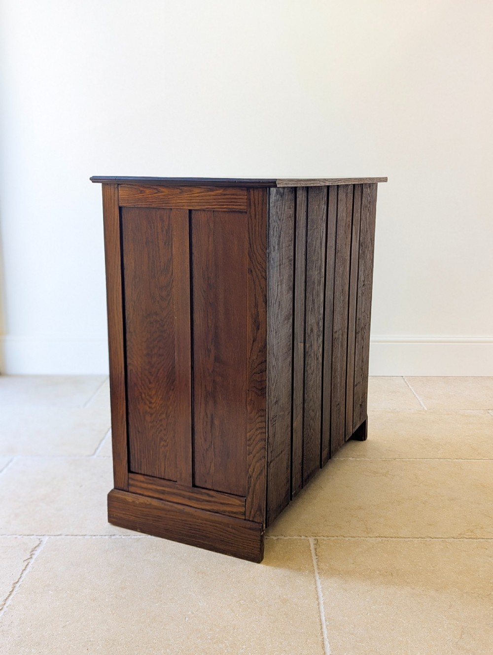 An Edwardian oak chest of drawers featuring a two over three layout with geometric boxwood inlay and dark metal drop handles on a plinth base. View XVII