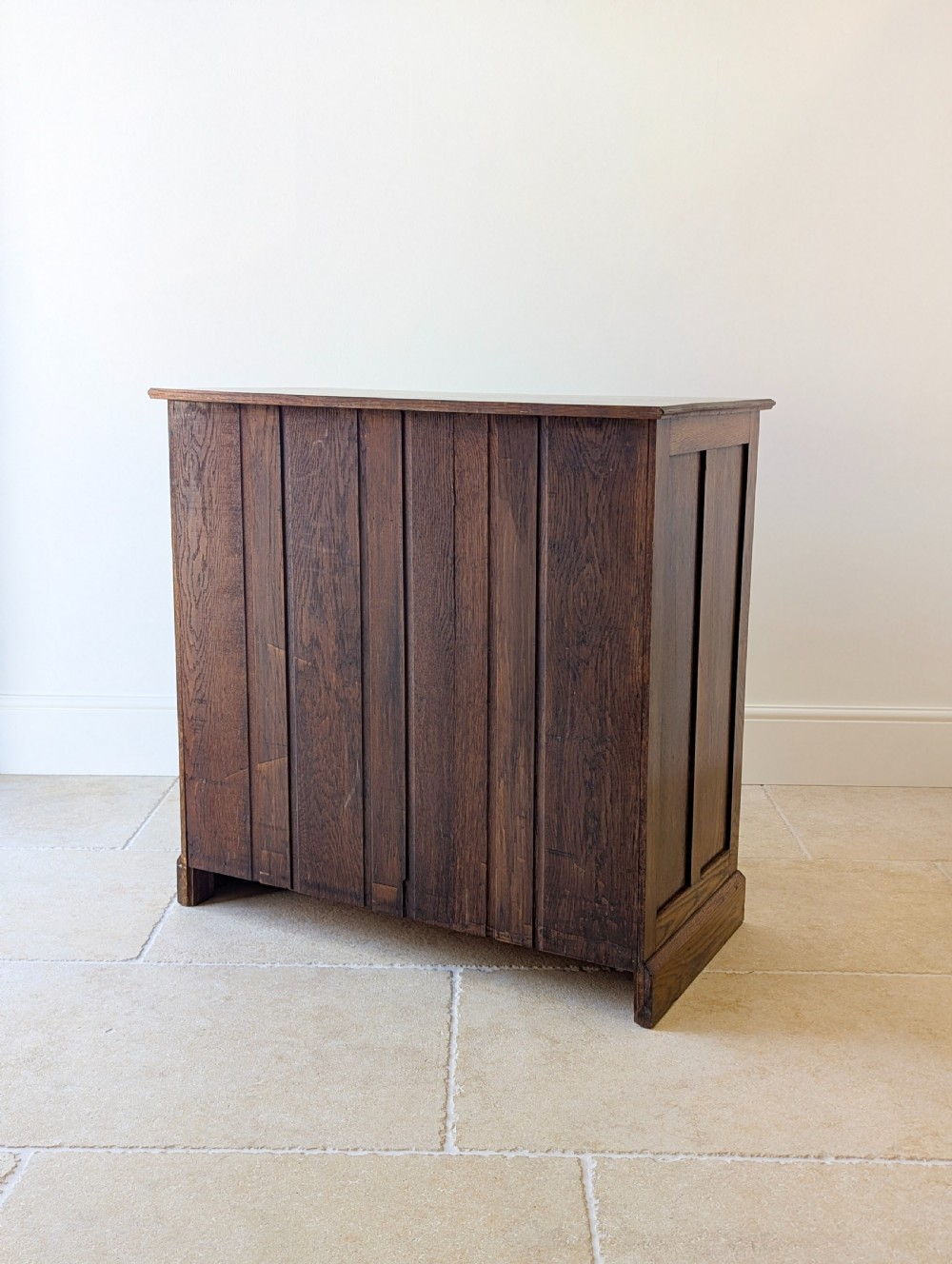 An Edwardian oak chest of drawers featuring a two over three layout with geometric boxwood inlay and dark metal drop handles on a plinth base. View XVIII