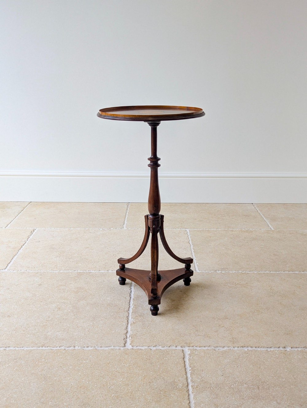 An Edwardian mahogany wine table featuring a circular top with a raised moulded edge, supported by a turned pedestal column and a triform base on small bun feet. View III
