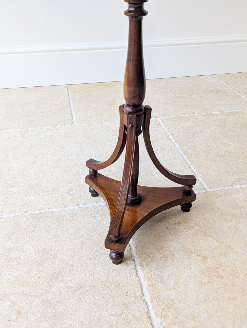 An Edwardian mahogany wine table featuring a circular top with a raised moulded edge, supported by a turned pedestal column and a triform base on small bun feet. View VI