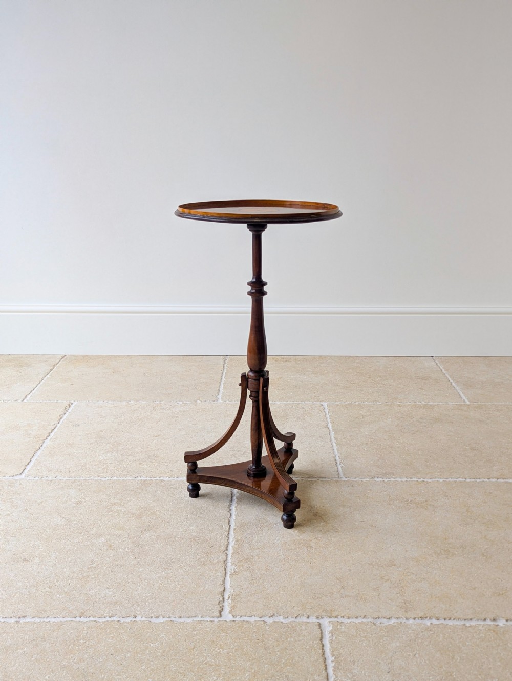An Edwardian mahogany wine table featuring a circular top with a raised moulded edge, supported by a turned pedestal column and a triform base on small bun feet. View VII