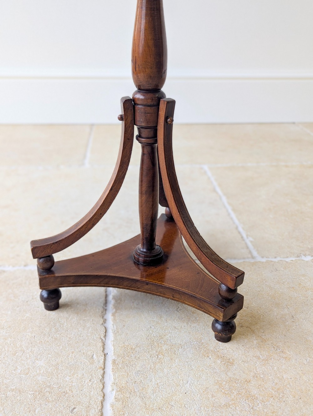 An Edwardian mahogany wine table featuring a circular top with a raised moulded edge, supported by a turned pedestal column and a triform base on small bun feet. View VIII
