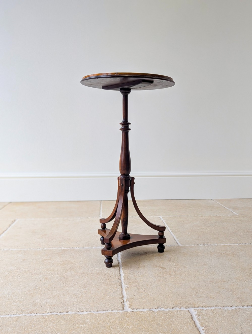 An Edwardian mahogany wine table featuring a circular top with a raised moulded edge, supported by a turned pedestal column and a triform base on small bun feet. View XI
