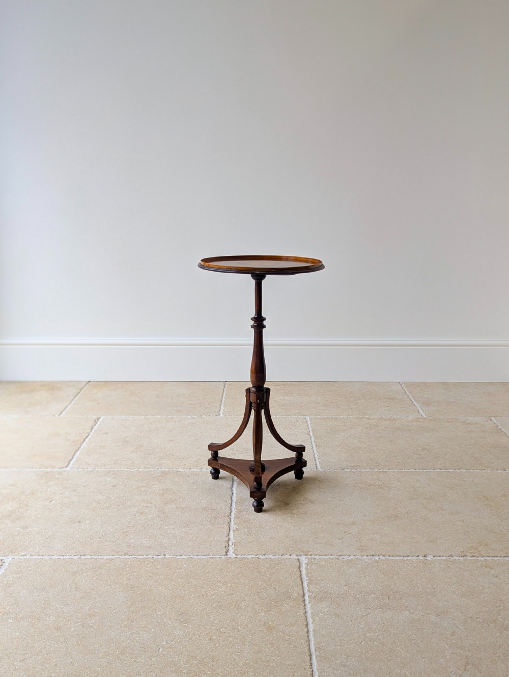 An Edwardian mahogany wine table featuring a circular top with a raised moulded edge, supported by a turned pedestal column and a triform base on small bun feet. View XIV