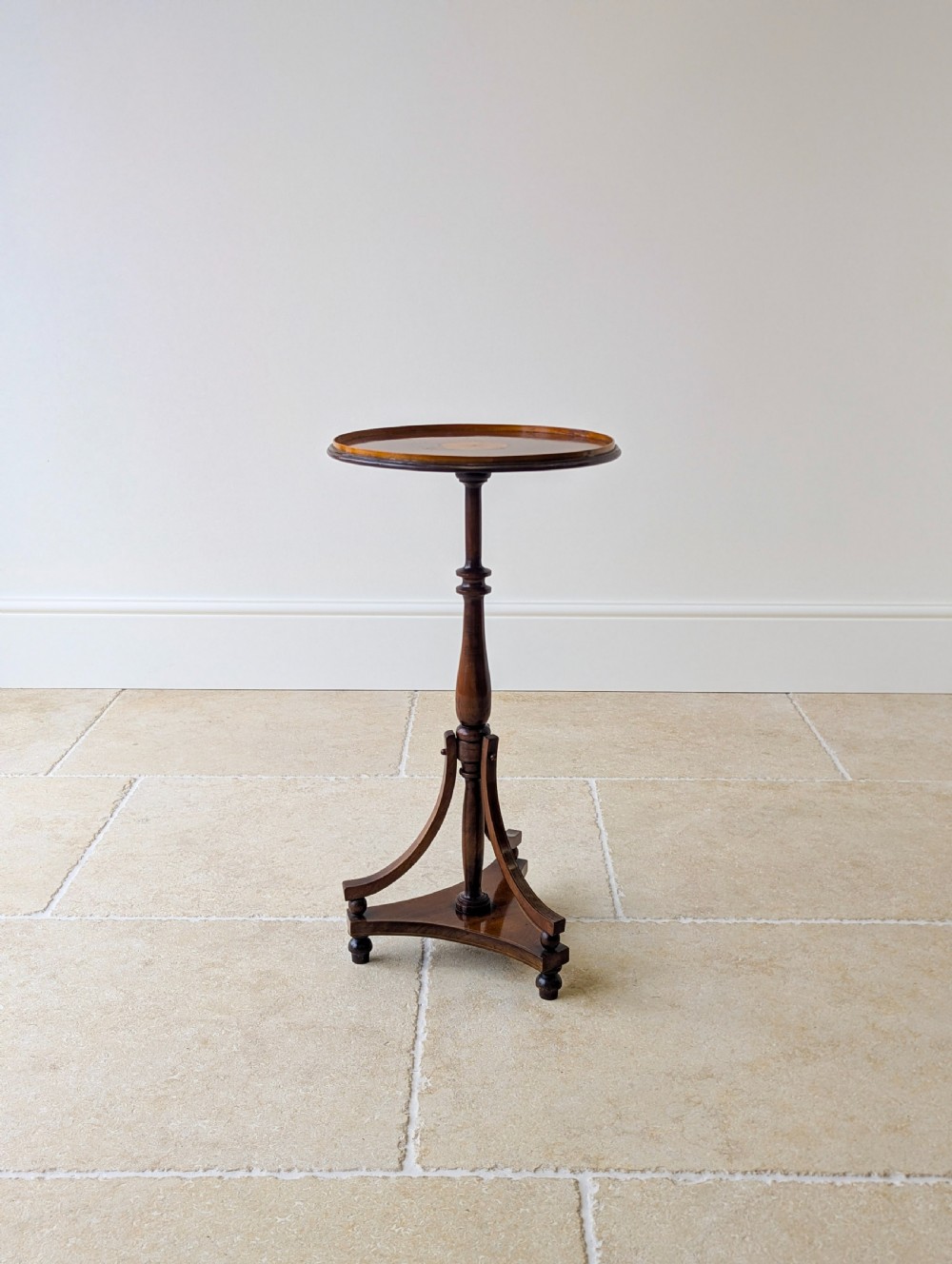 An Edwardian mahogany wine table featuring a circular top with a raised moulded edge, supported by a turned pedestal column and a triform base on small bun feet. View XV