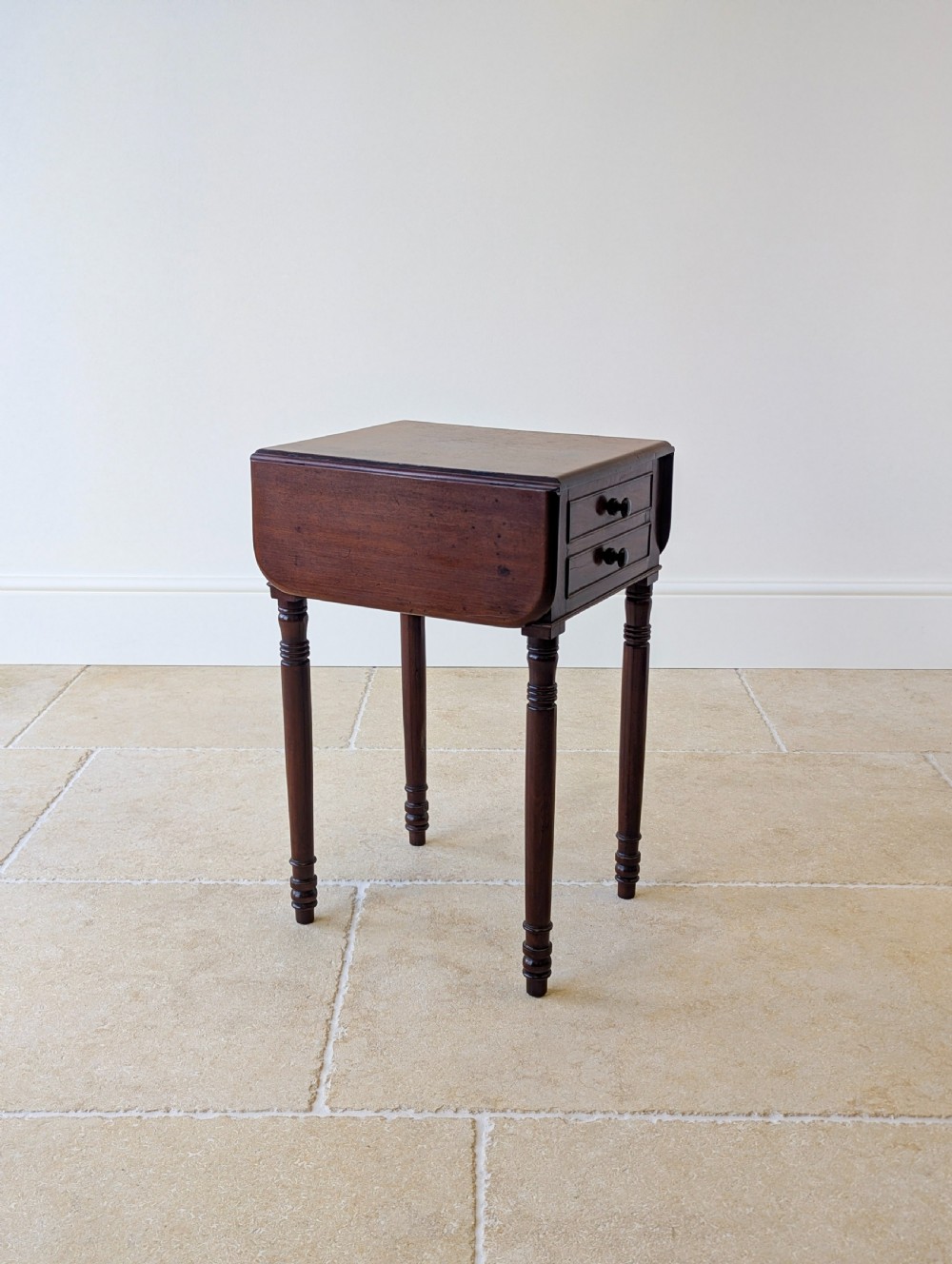 An early Victorian dark mahogany Pembroke work table with two drawers, turned legs, and two extended drop-leaf flaps. View II