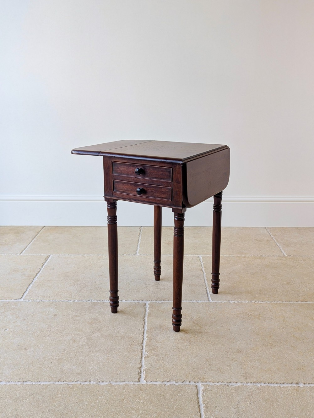 An early Victorian dark mahogany Pembroke work table with two drawers, turned legs, and two extended drop-leaf flaps. View III