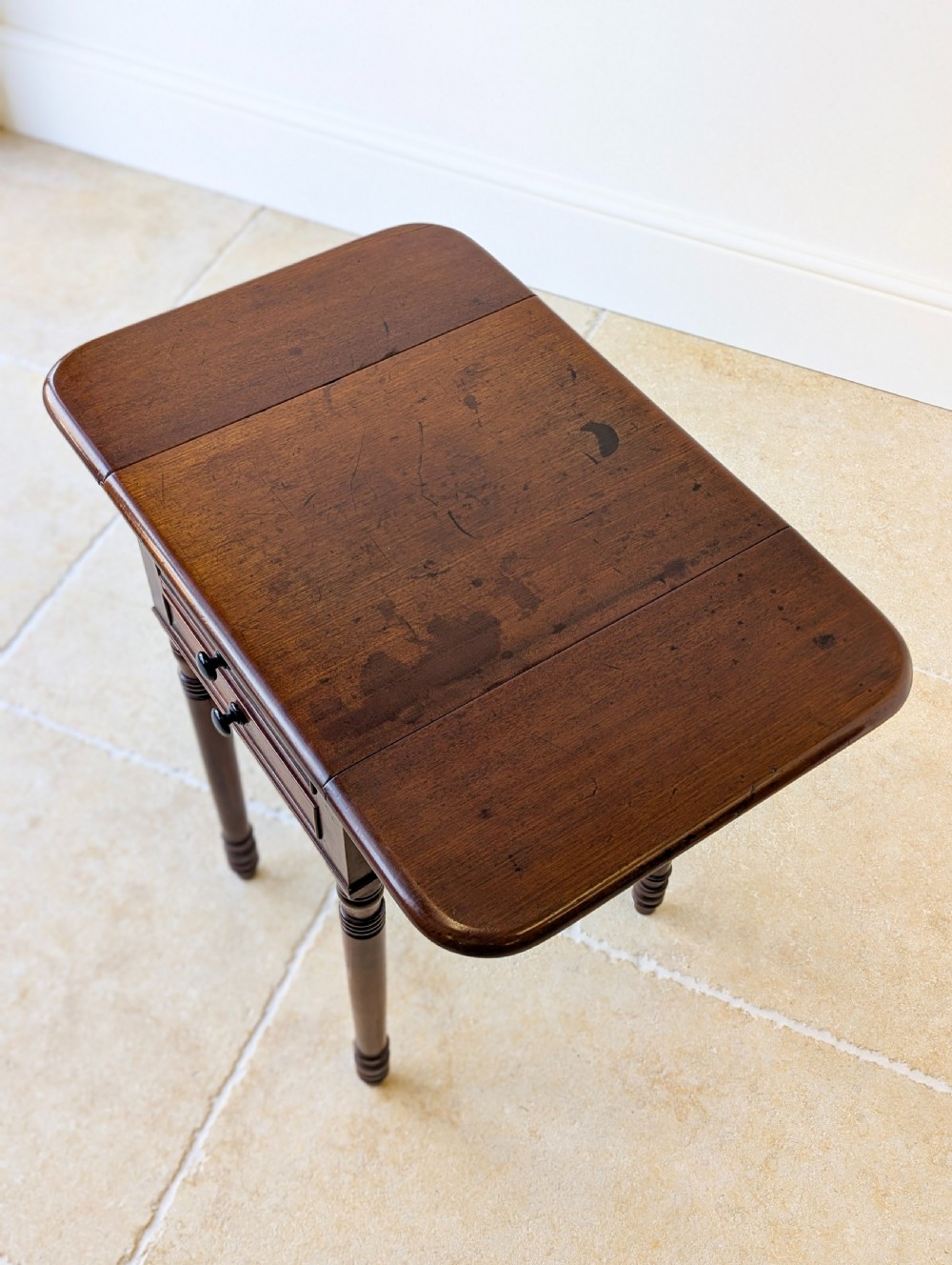 An early Victorian dark mahogany Pembroke work table with two drawers, turned legs, and two extended drop-leaf flaps. View IV