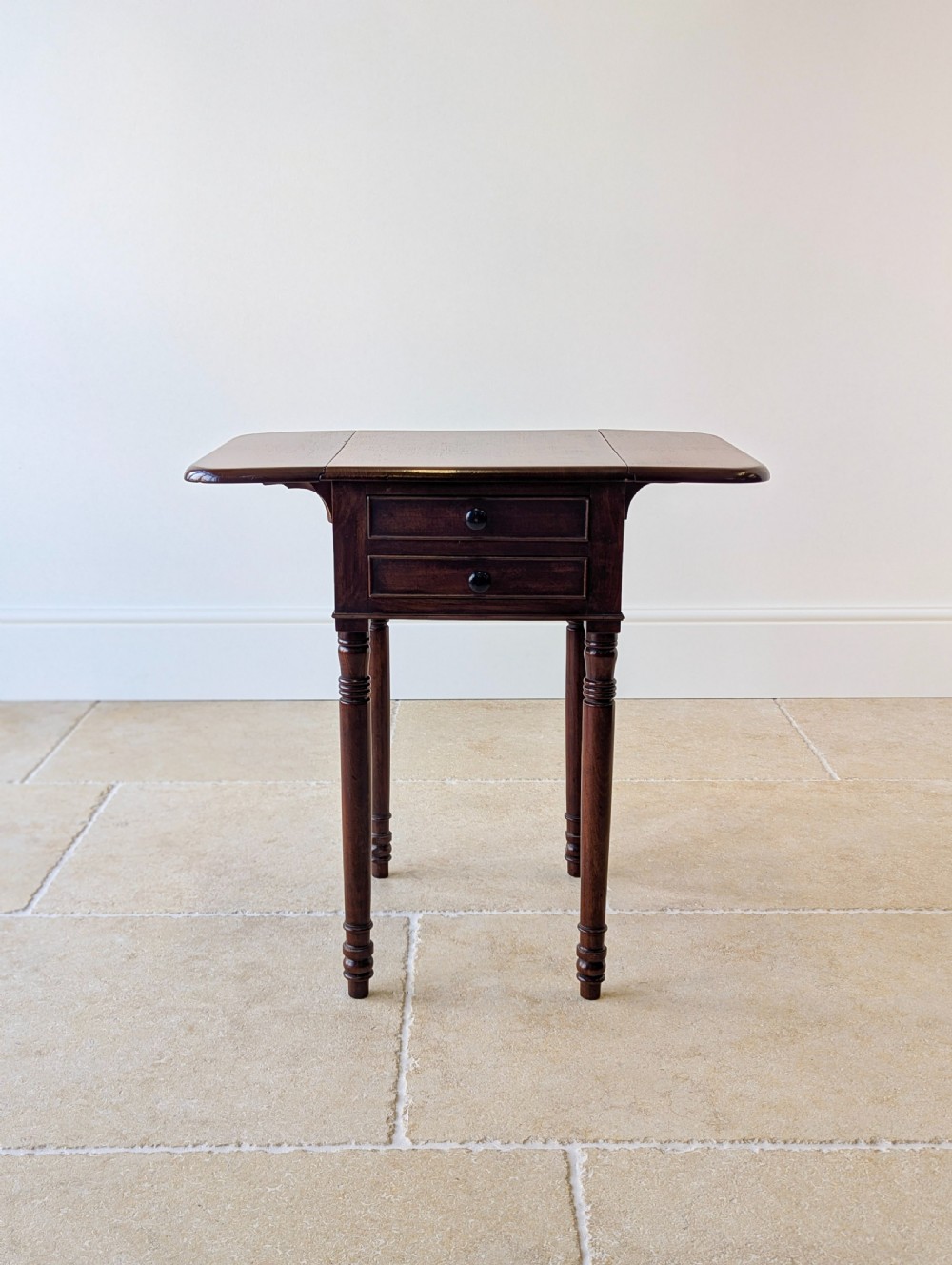 An early Victorian dark mahogany Pembroke work table with two drawers, turned legs, and two extended drop-leaf flaps. View V