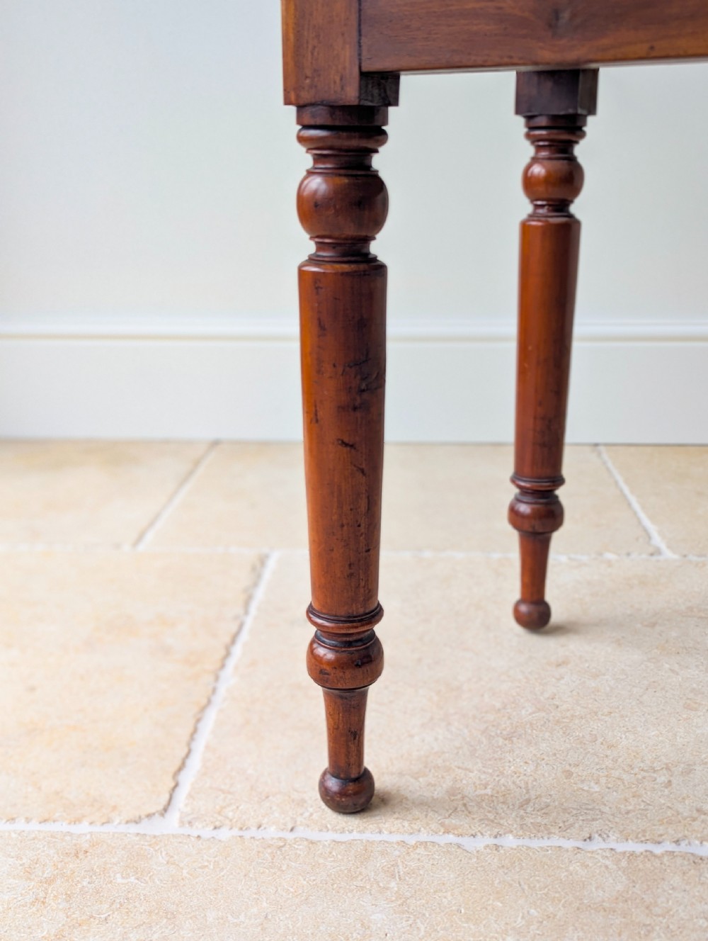 A Victorian mahogany writing table featuring two front drawers with dark turned knobs, a raised rear gallery upstand, and four turned legs. View VII