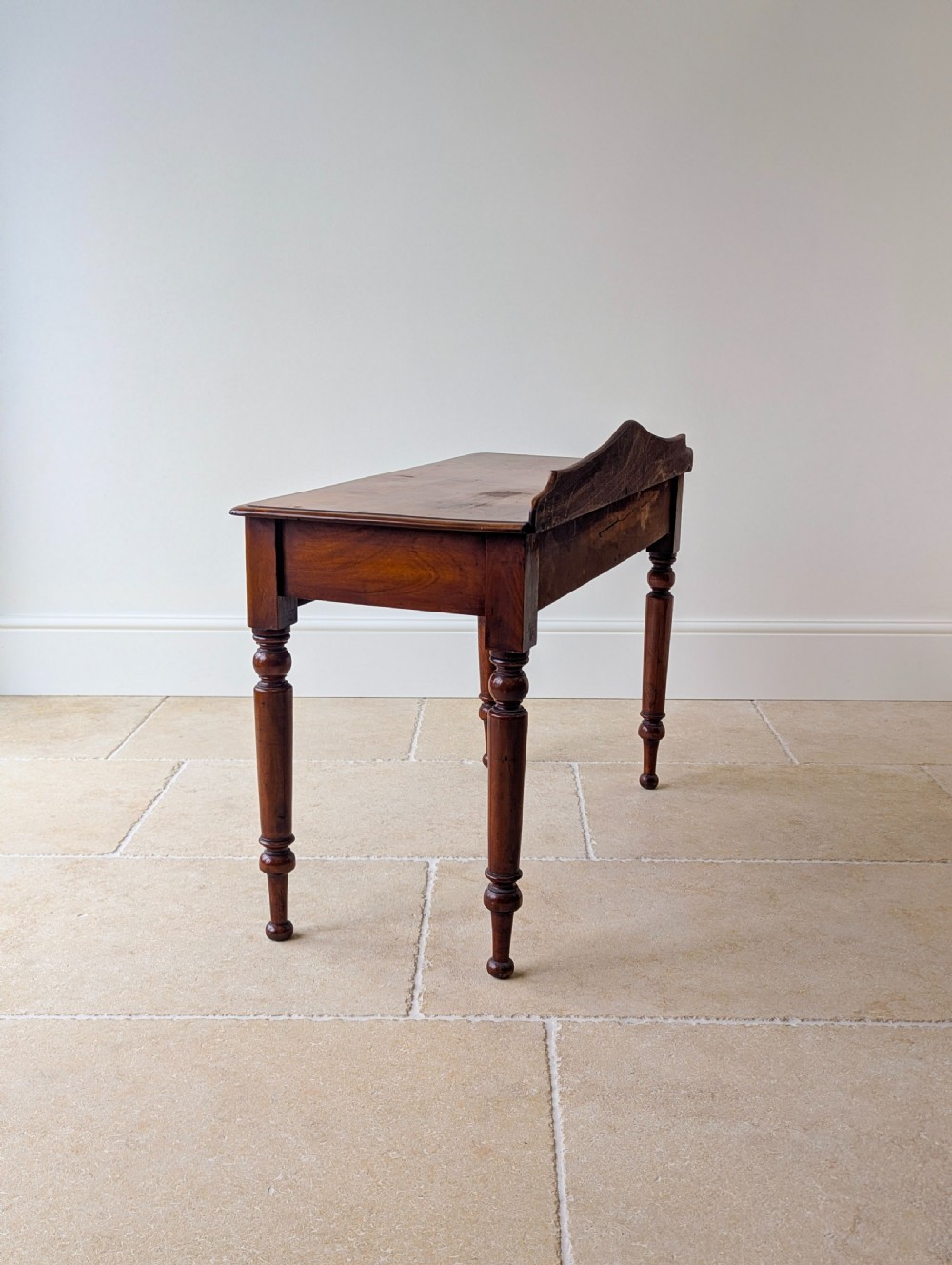 A Victorian mahogany writing table featuring two front drawers with dark turned knobs, a raised rear gallery upstand, and four turned legs. View XIII