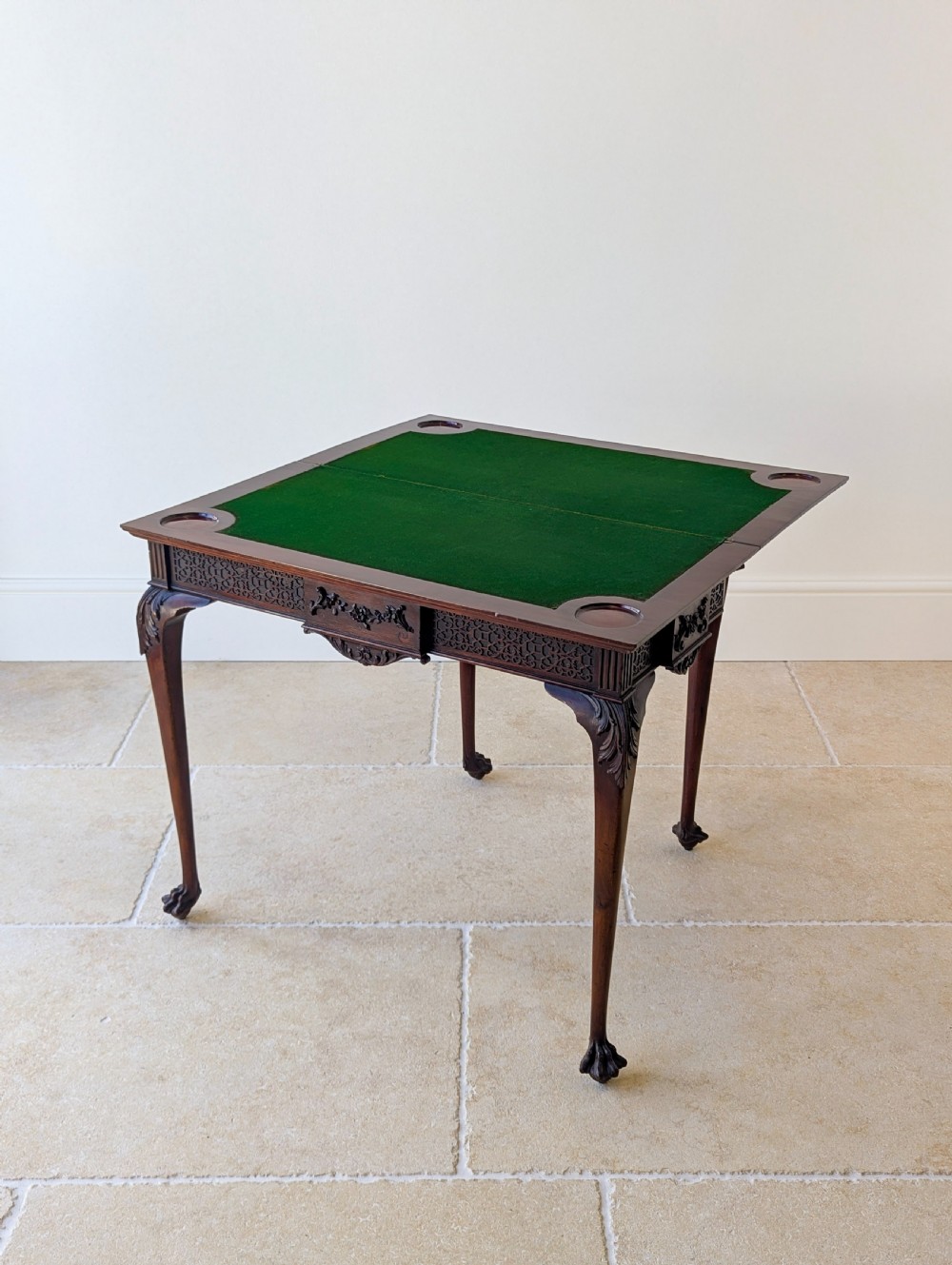 An Edwardian dark mahogany fold-over card table featuring carved cabriole legs, claw and ball feet, and blind fretwork along the apron. View II