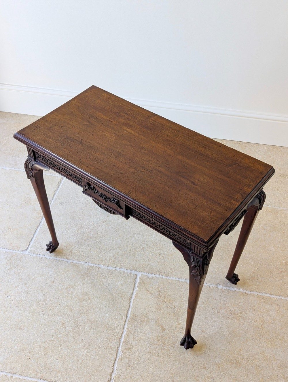 An Edwardian dark mahogany fold-over card table featuring carved cabriole legs, claw and ball feet, and blind fretwork along the apron. View III