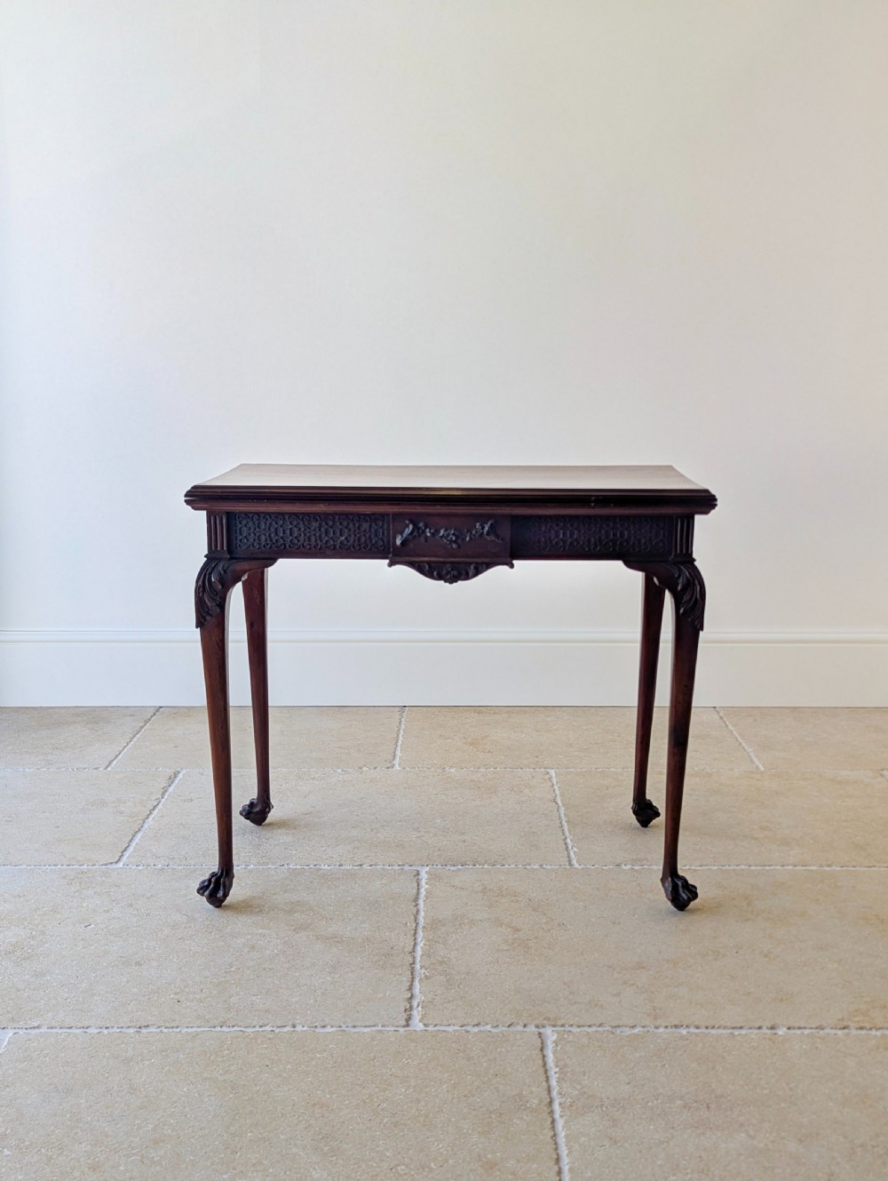 An Edwardian dark mahogany fold-over card table featuring carved cabriole legs, claw and ball feet, and blind fretwork along the apron. View V