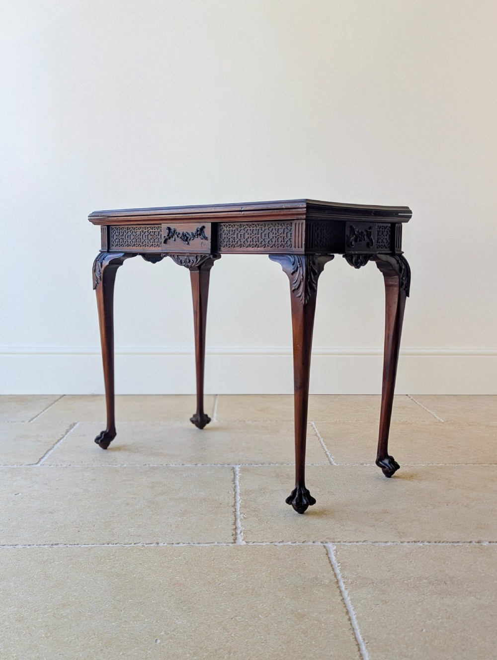 An Edwardian dark mahogany fold-over card table featuring carved cabriole legs, claw and ball feet, and blind fretwork along the apron. View VII