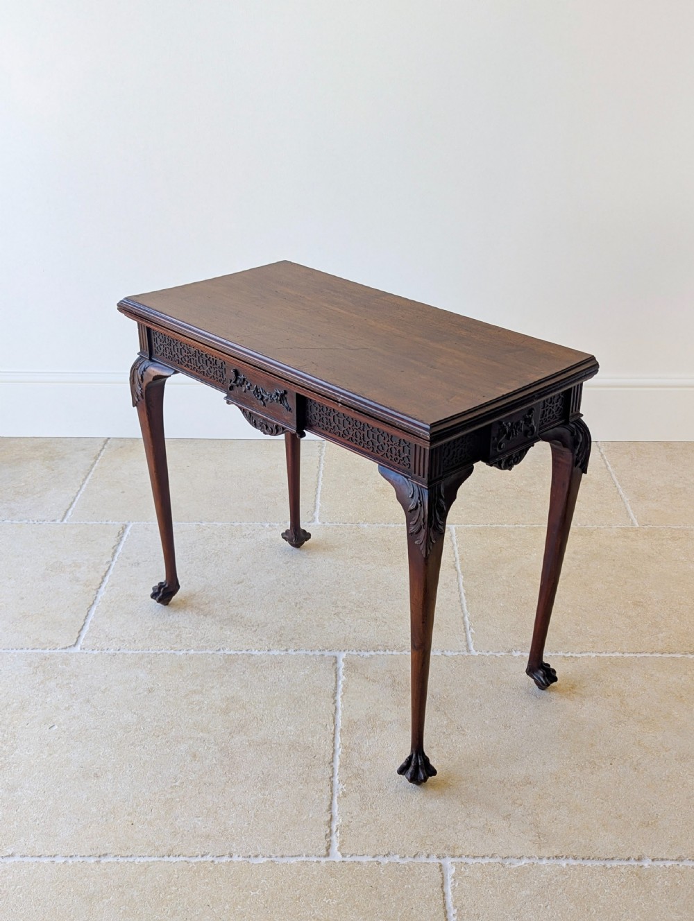 An Edwardian dark mahogany fold-over card table featuring carved cabriole legs, claw and ball feet, and blind fretwork along the apron. View XI
