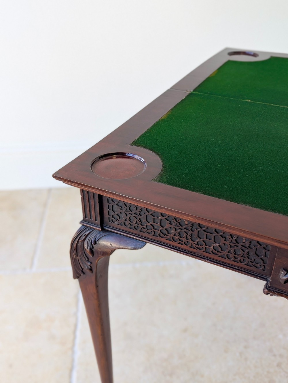 An Edwardian dark mahogany fold-over card table featuring carved cabriole legs, claw and ball feet, and blind fretwork along the apron. View XII