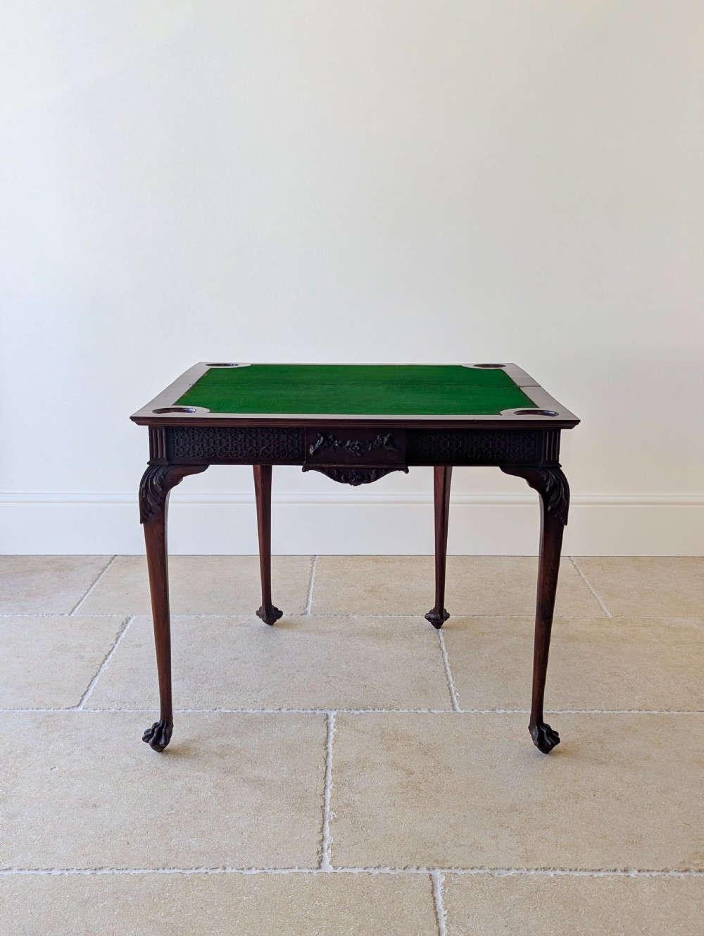 An Edwardian dark mahogany fold-over card table featuring carved cabriole legs, claw and ball feet, and blind fretwork along the apron. View XIV
