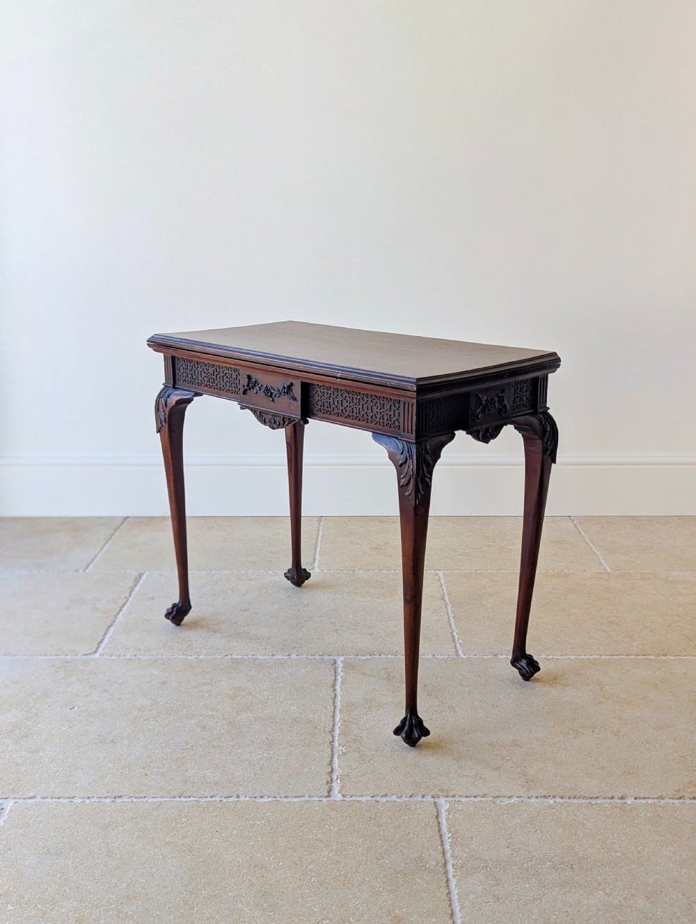 An Edwardian dark mahogany fold-over card table featuring carved cabriole legs, claw and ball feet, and blind fretwork along the apron. View XV