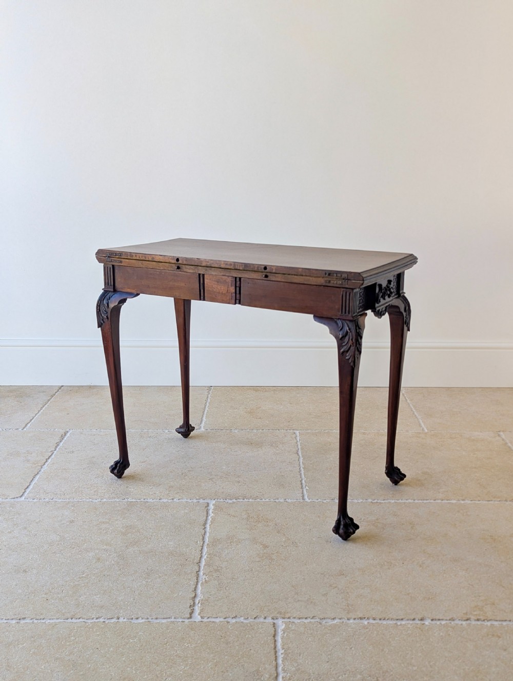 An Edwardian dark mahogany fold-over card table featuring carved cabriole legs, claw and ball feet, and blind fretwork along the apron. View XVI