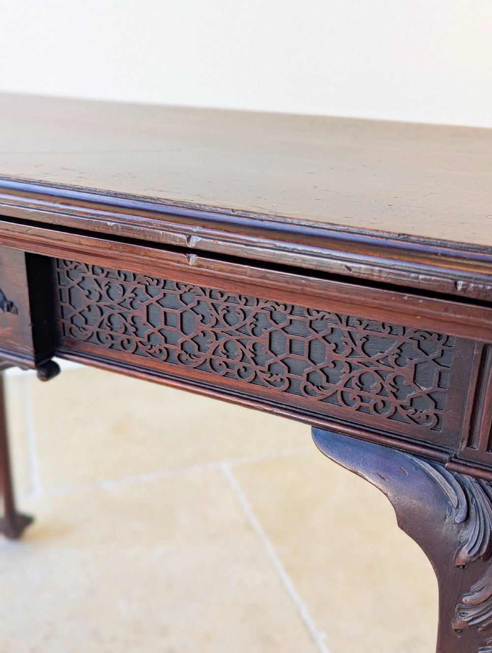 An Edwardian dark mahogany fold-over card table featuring carved cabriole legs, claw and ball feet, and blind fretwork along the apron. View XVII
