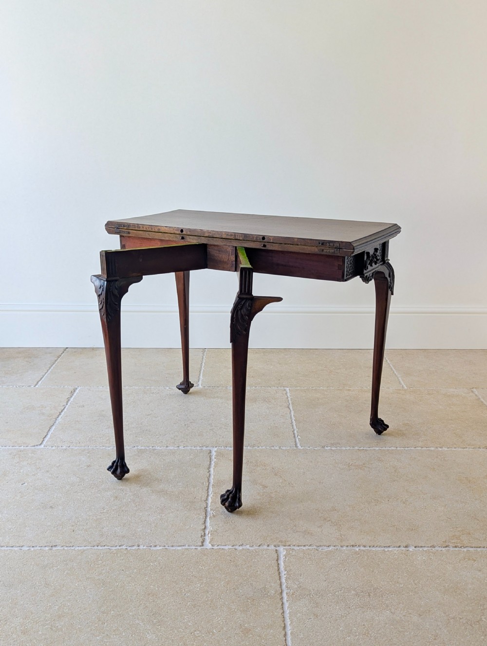 An Edwardian dark mahogany fold-over card table featuring carved cabriole legs, claw and ball feet, and blind fretwork along the apron. View XVIII