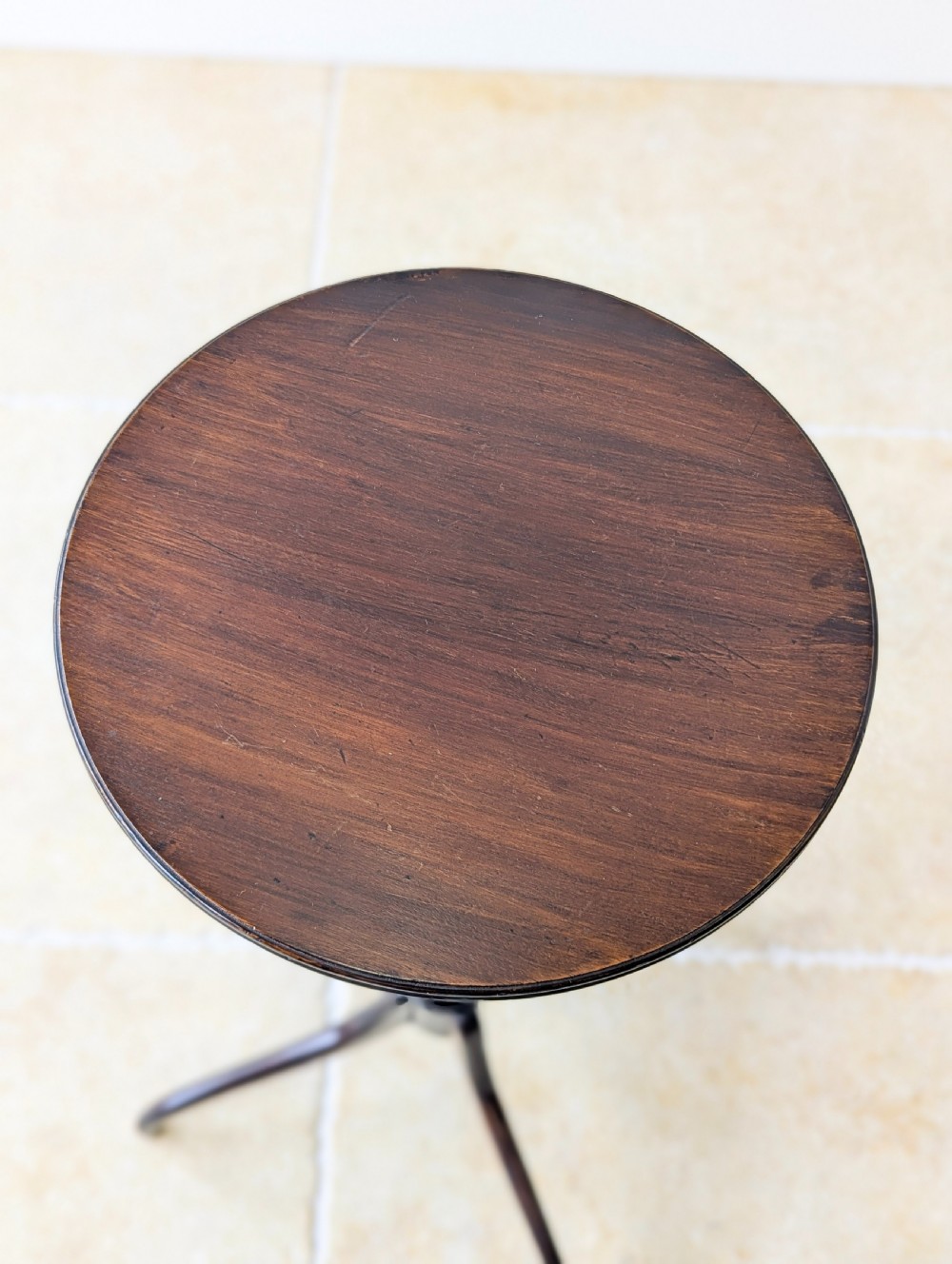 A tall, slender dark walnut torchere featuring a circular flat top, a turned central column, and a sweeping tripod base. View III