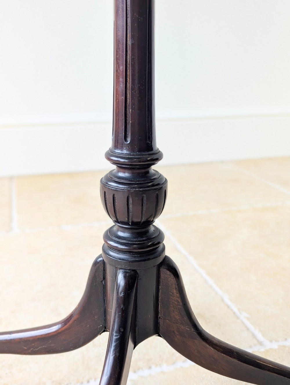 A tall, slender dark walnut torchere featuring a circular flat top, a turned central column, and a sweeping tripod base. View V