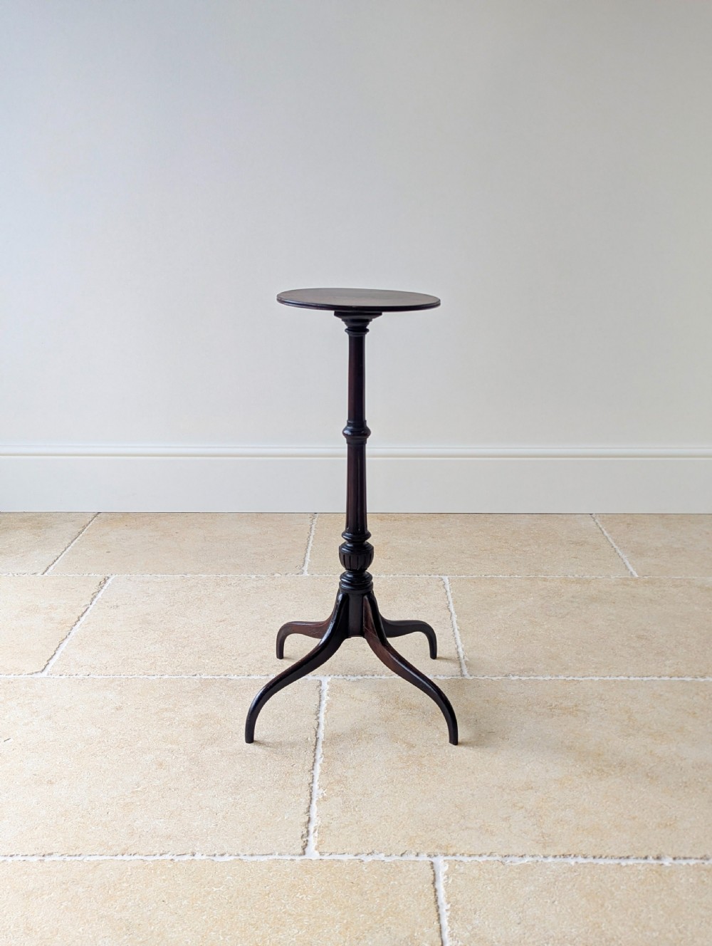 A tall, slender dark walnut torchere featuring a circular flat top, a turned central column, and a sweeping tripod base. View VI