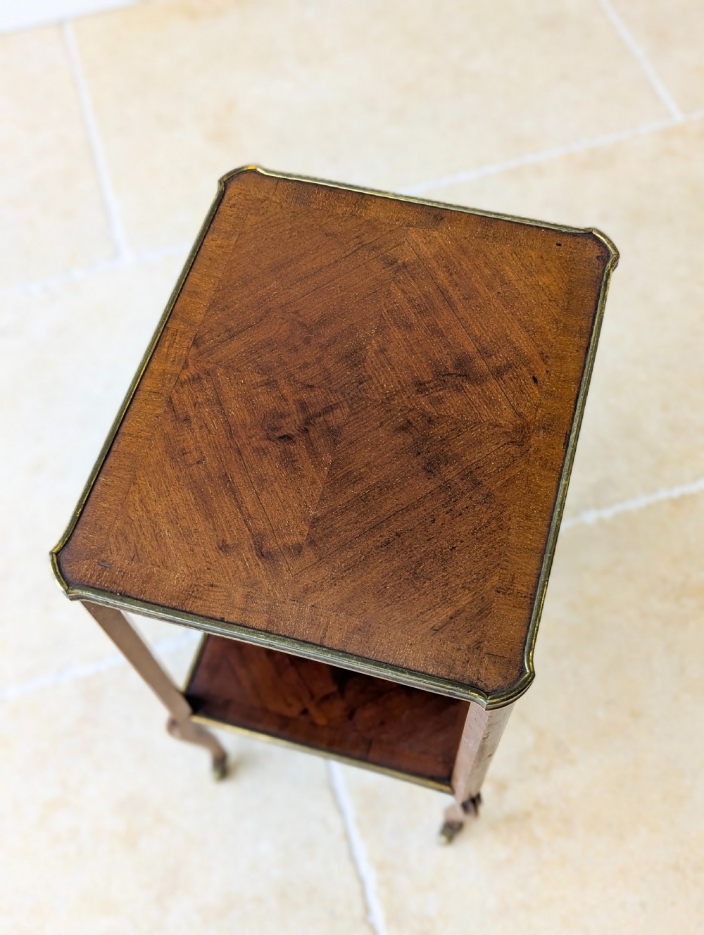 A late Victorian square mahogany two-tier occasional table with cabriole legs, brass-edged rims, and brass castors. View III